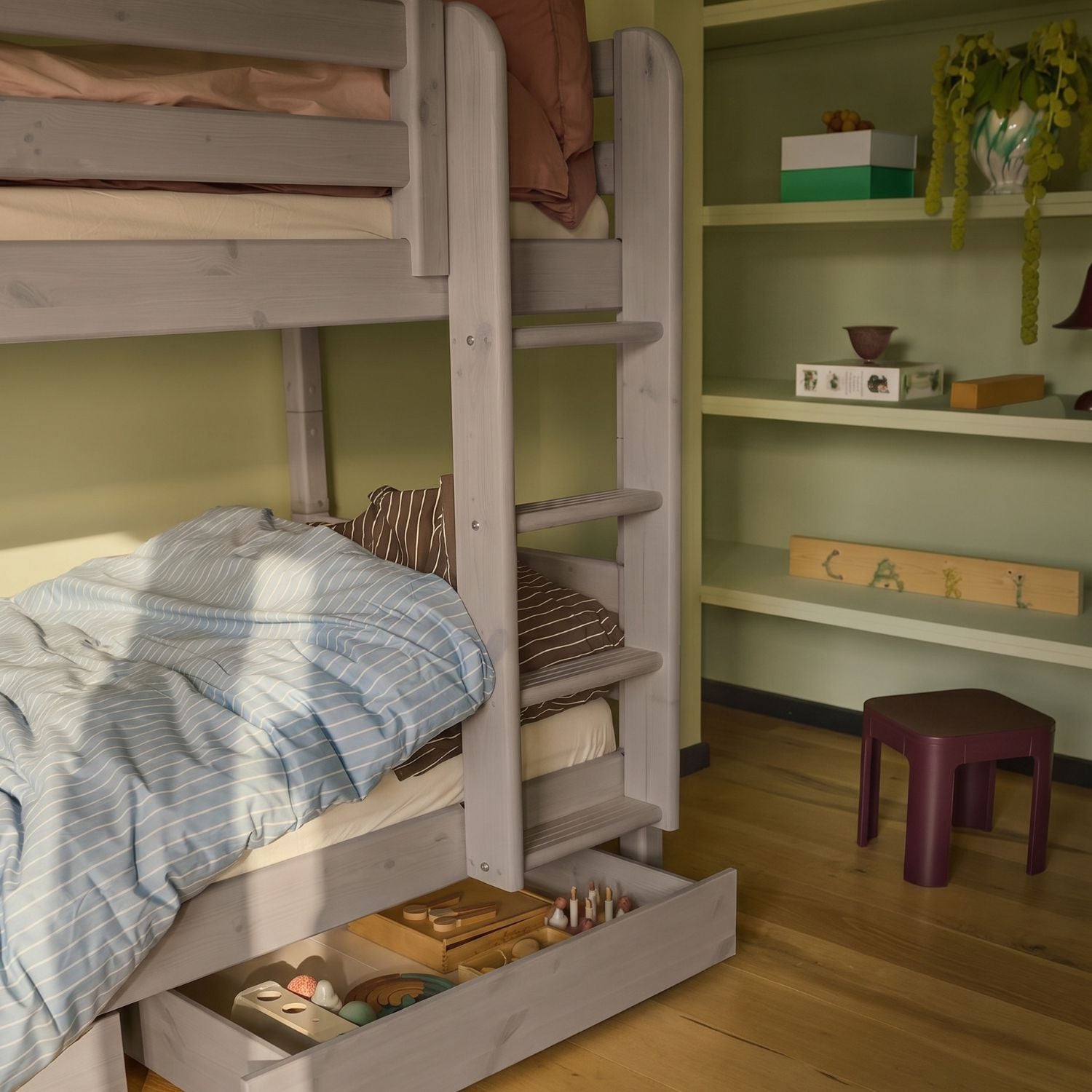 Cajones marrones FLEXA para debajo de la cama de la gama CLASSIC, con ropa de cama a rayas azules y estantes, con un diseño seguro para los niños en una habitación infantil.
