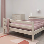 Cama individual blanca FLEXA de la colección CLASSIC en una habitación infantil minimalista con ropa de cama, cómoda y alfombra de color rosa.