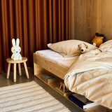 Taburete infantil FLEXA DOTS en rosa pálido, con un diseño apto para niños, en una habitación infantil con cama de madera y cortina naranja.