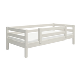 Cama individual FLEXA CLASSIC de pino blanco con barandilla de seguridad, mostrada en una habitación infantil sobre un fondo blanco.