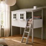 Cama FLEXA MID-HIGH con estructura y escalera en blanco y gris, diseño seguro para niños, en una habitación verde con suelo de madera.